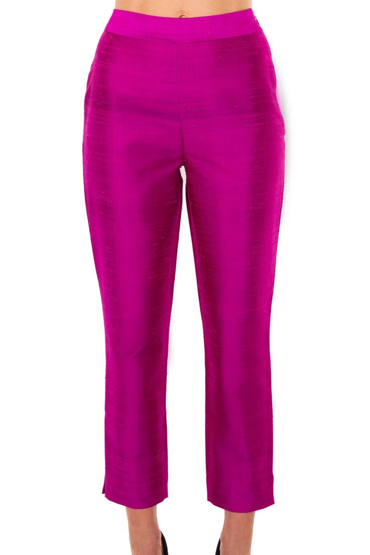 a woman is wearing a pair of fuchsia pink, slim fit, silk pants. the pants are cropped and have a high waist. they are  casual wear.