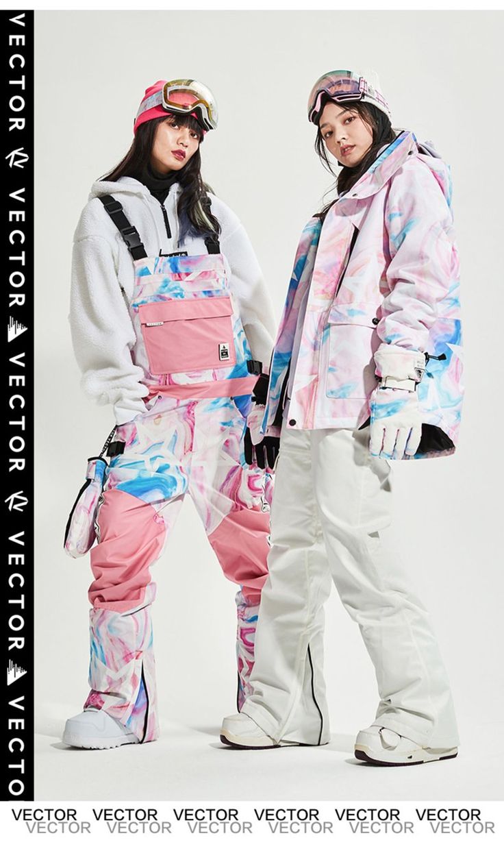 two young female models are wearing colorful ski suits while posing for the camera in a studio.  the girl on the left is wearing a pink and white jacket and matching pants with a beanie and goggles.  the girl on the right is wearing a white and pink jacket with white pants and a beanie and goggles.  they are standing in front of a white background and are looking at the camera.