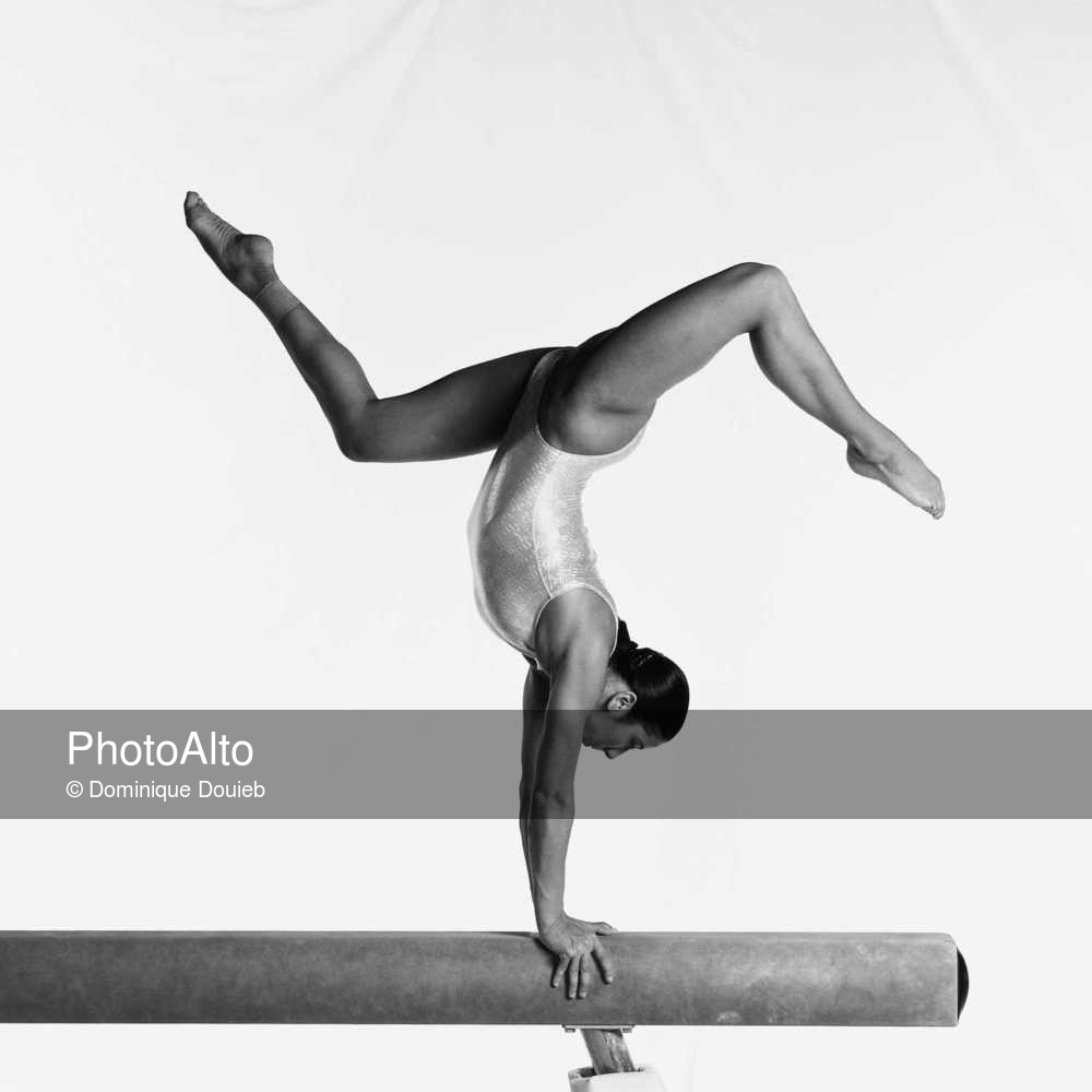 Young female gymnast on balance beam performing routine, side view - Photoa...