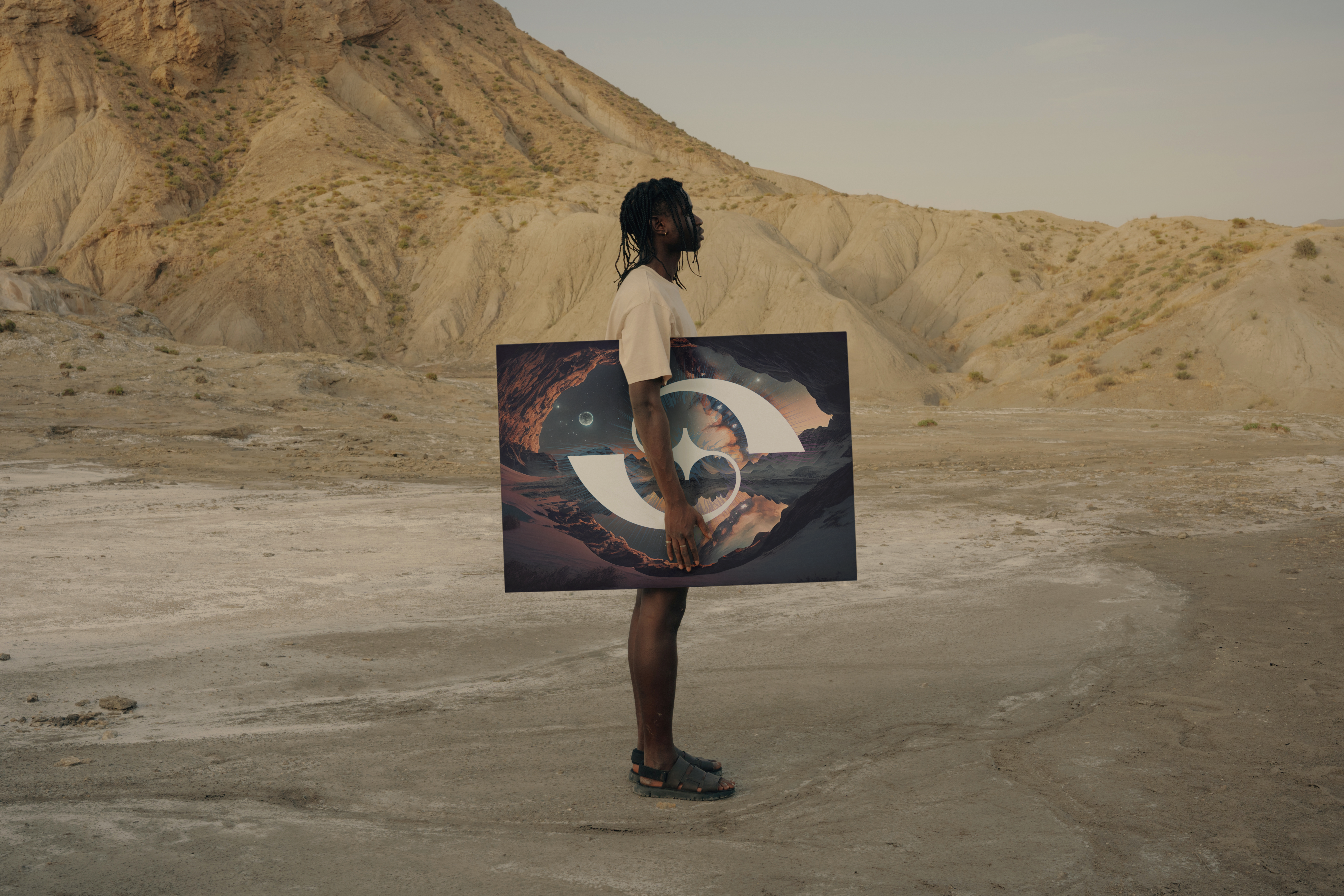 Person holding a futuristic portal frame in a desert landscape with rocky cliffs in the background