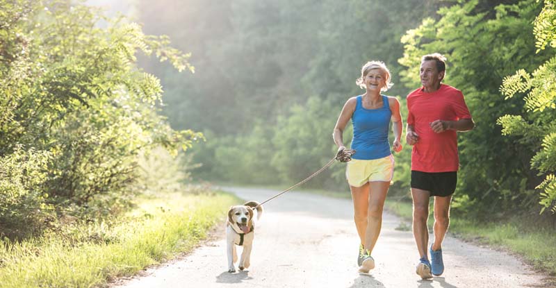 Jogging couple with their dog on a rural road in Crystal Lake, Illinois