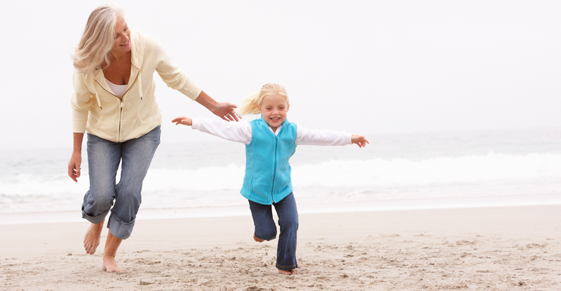 Grandmother in jeans on beach with granddaughter