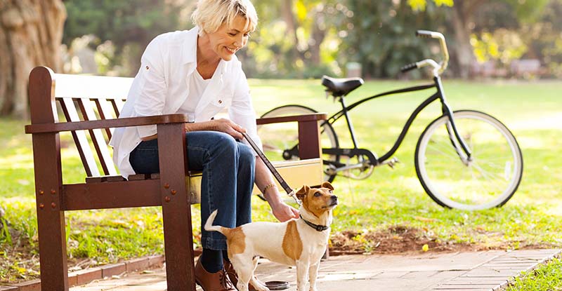 Older woman with her bike and dog on a park bench in Spring Grove, Illinois