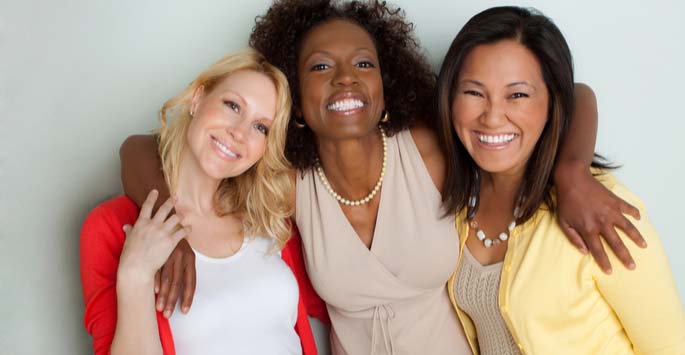 Three female friends smiling and embracing each other