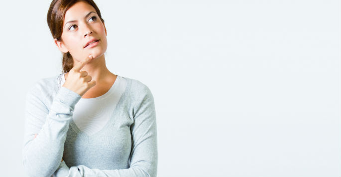 Brunette 30-year old with finger on chin contemplating micro-needling