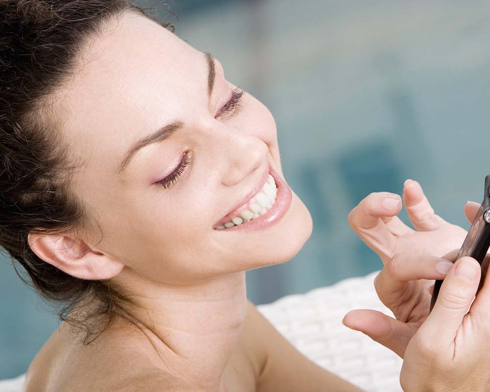 Close up of woman's freshly showered wrinkle-free face while she dials her cell phone