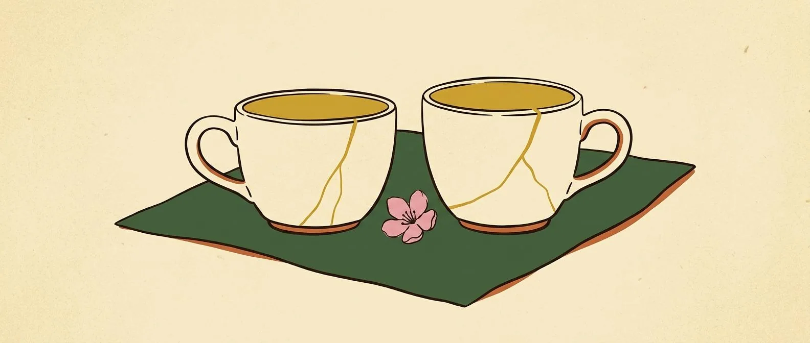 Two repaired ceramic cups resting together with a small flower.