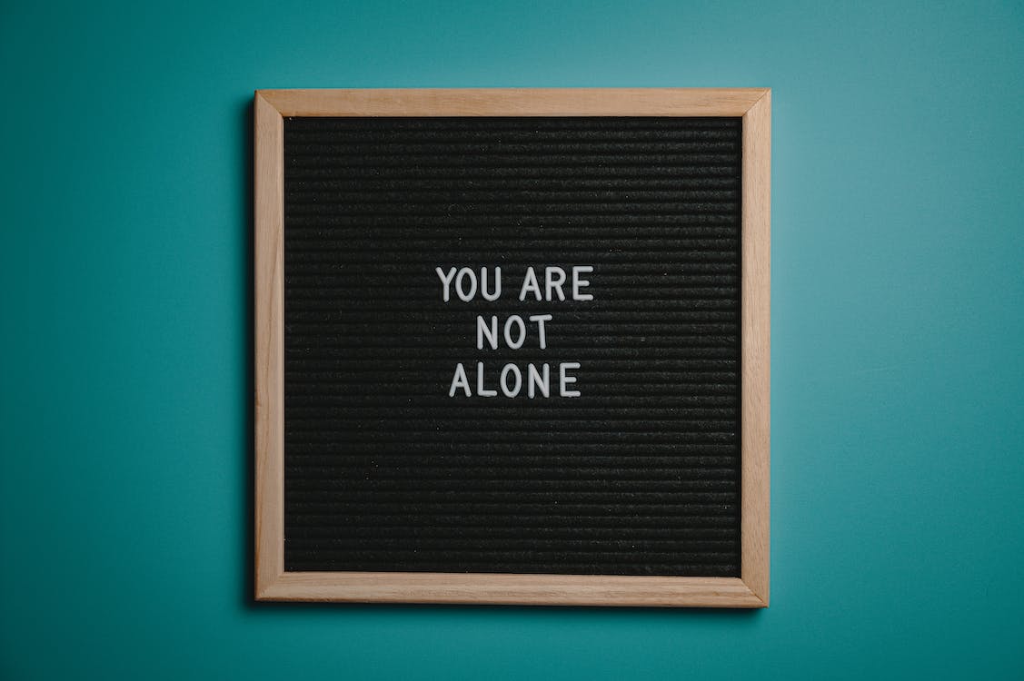 Free You Are Not Alone Quote Board on Brown Wooden Frame Stock Photo