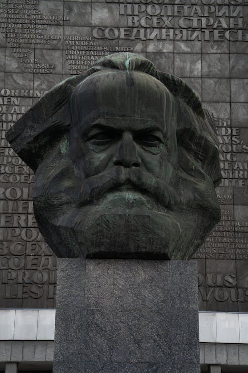 Free Stone head sculpture of revolutionary placed on high postament against stone wall in city Stock Photo