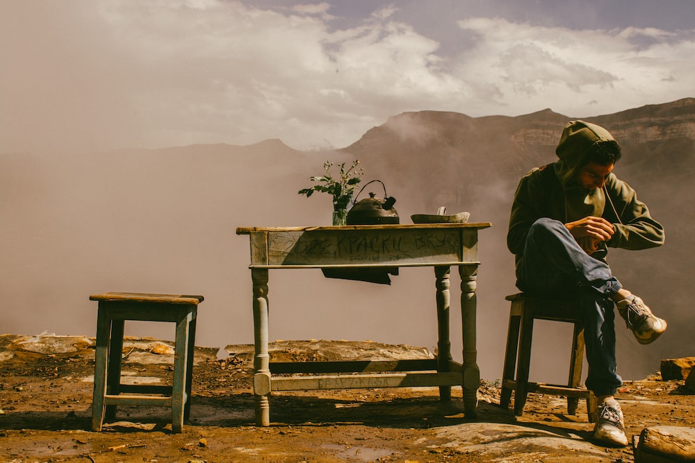 um homem sentado em uma mesa no topo de uma montanha