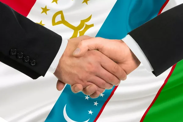 A handshake symbolizes cooperation between Uzbekistan and Tajikistan on economic ventures.