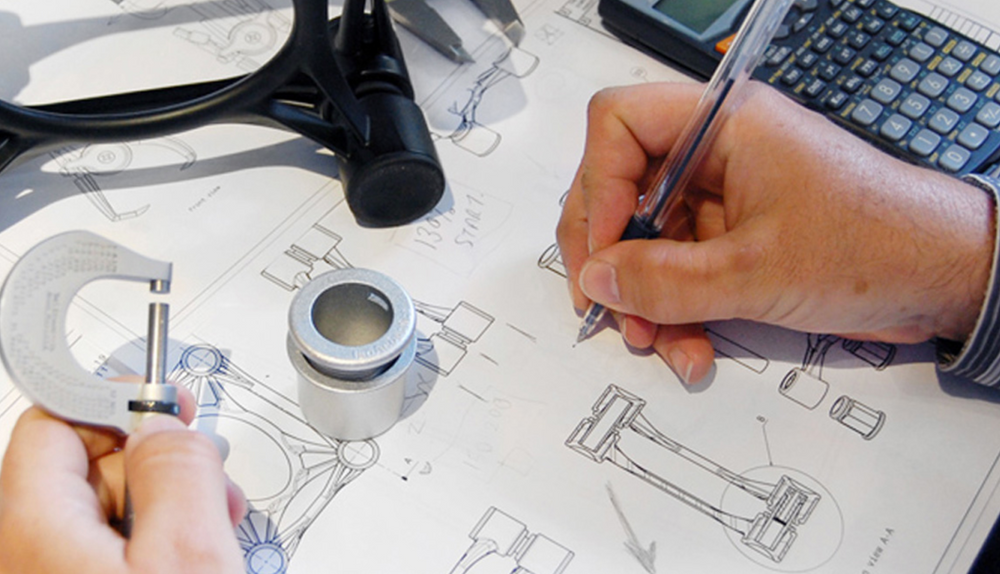 Diseñador trazando planos de piezas mecánicas con micrómetro y calculadora sobre la mesa