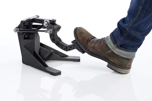 Pedal automotriz impreso en material negro reforzado, accionado por un pie para mostrar su resistencia