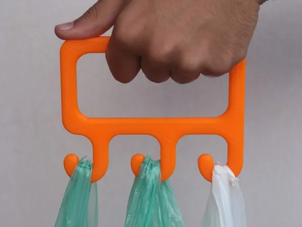 Mano levantando bolsas con un gancho naranja impreso en 3D, pieza que requiere alta densidad
