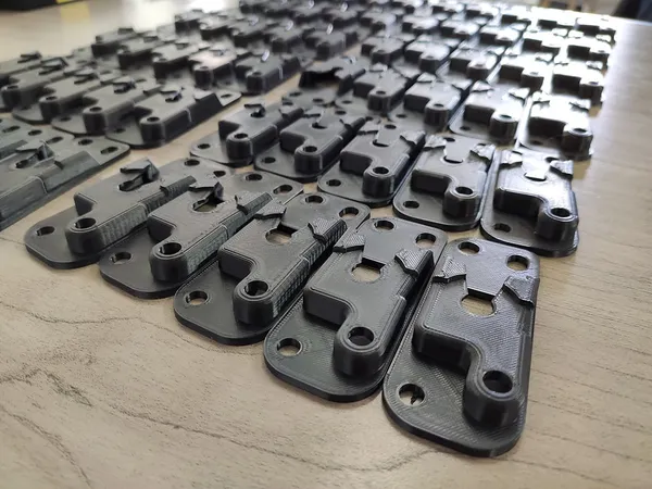 Serie de piezas negras para arnés automotriz impresas en 3D alineadas sobre una mesa