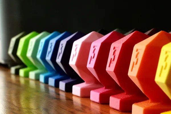 Fila de piezas impresas en PLA de muchos colores que muestra la variedad y consistencia de tonos