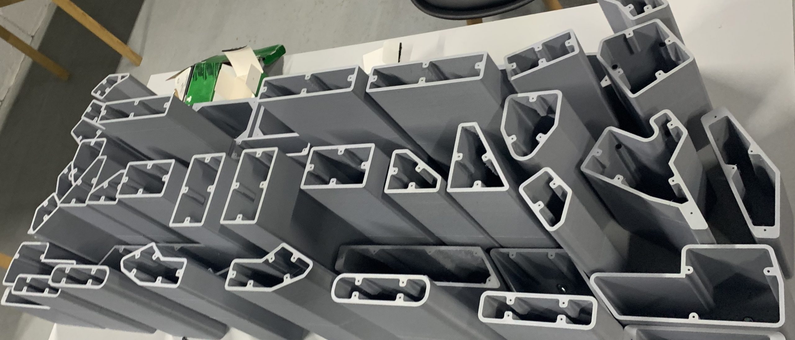 Conjunto de piezas grises impresas en 3D con perfiles huecos que forman un nido de ensamble automotriz