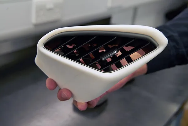Rejilla de ventilación automotriz impresa en 3D sostenida en la mano, ejemplo de pieza funcional