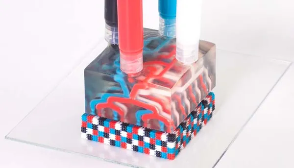 Bloque impreso en 3D con canales internos de varios colores que ilustra la impresión multimaterial