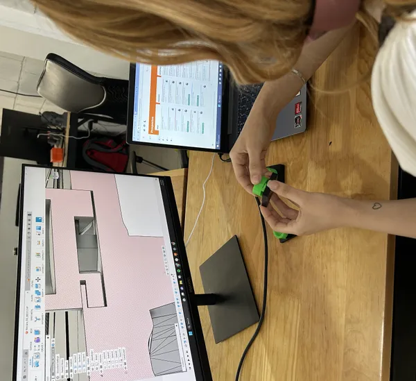 Diseñadora revisa una pieza verde impresa en 3D junto a su modelo en pantalla durante el proceso de diseño