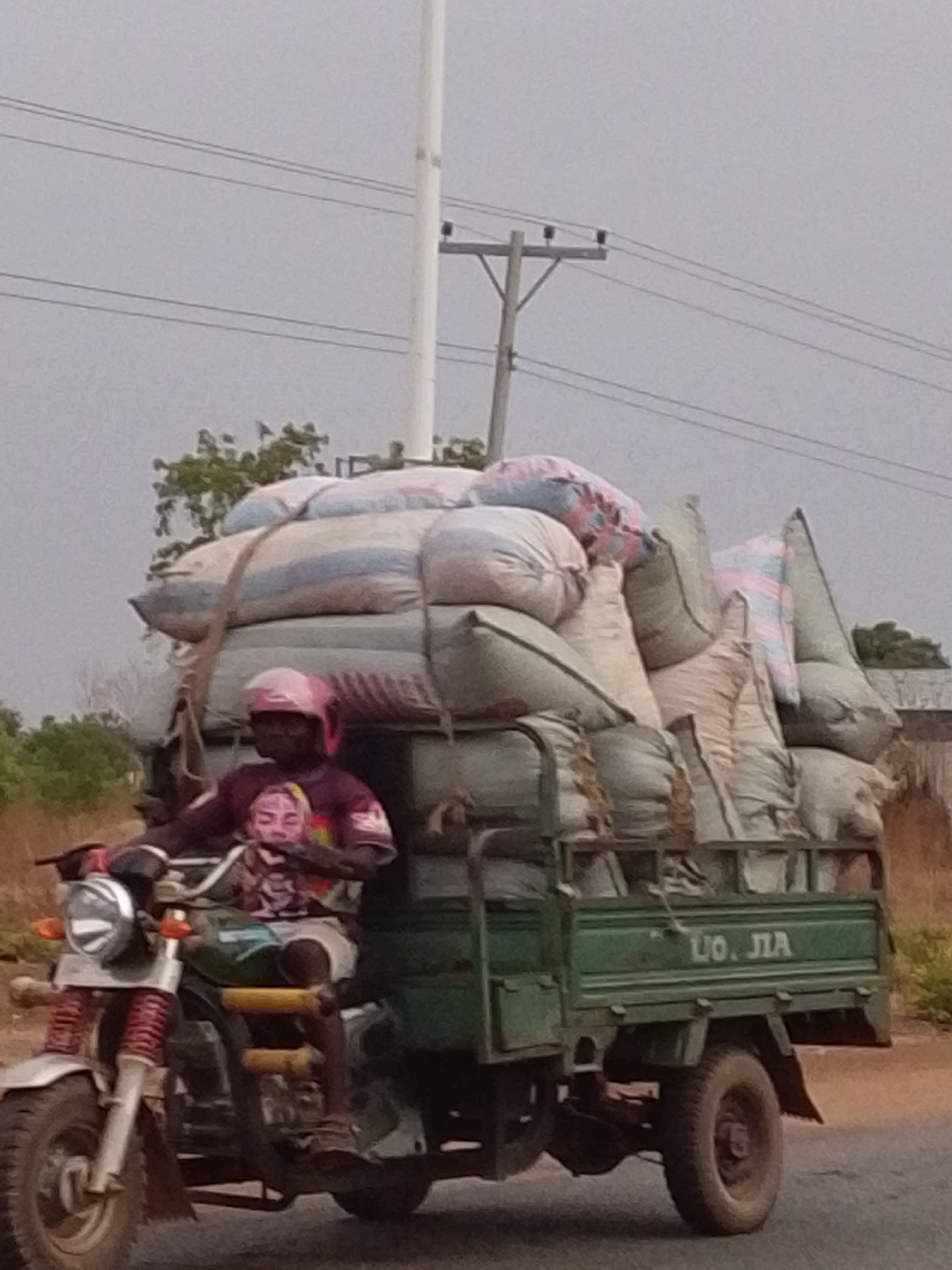 Tricycle motorcycle carries heavy cargo load in Dungu Ghana