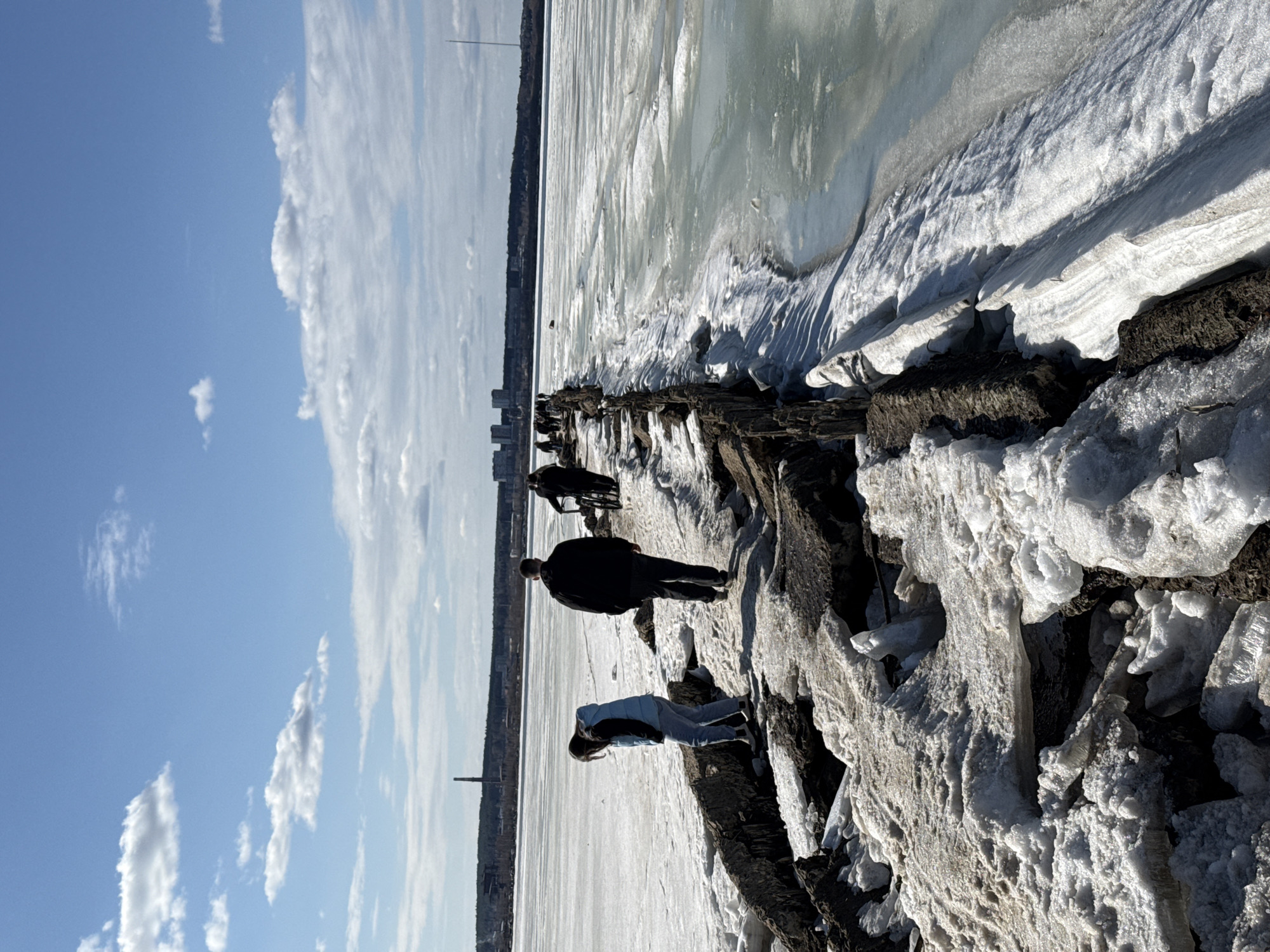 People walk on icy concrete structure near frozen water