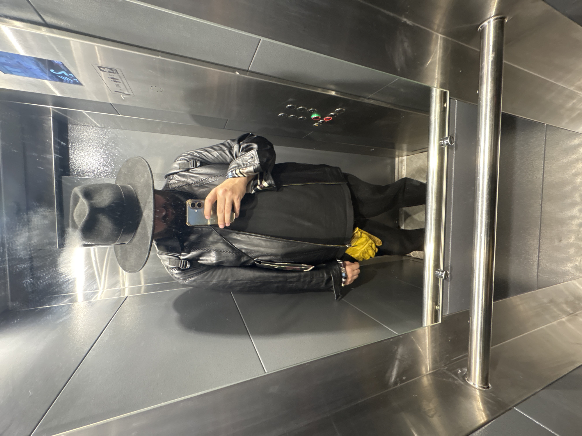 Person in hat and leather jacket photographed in Moscow elevator
