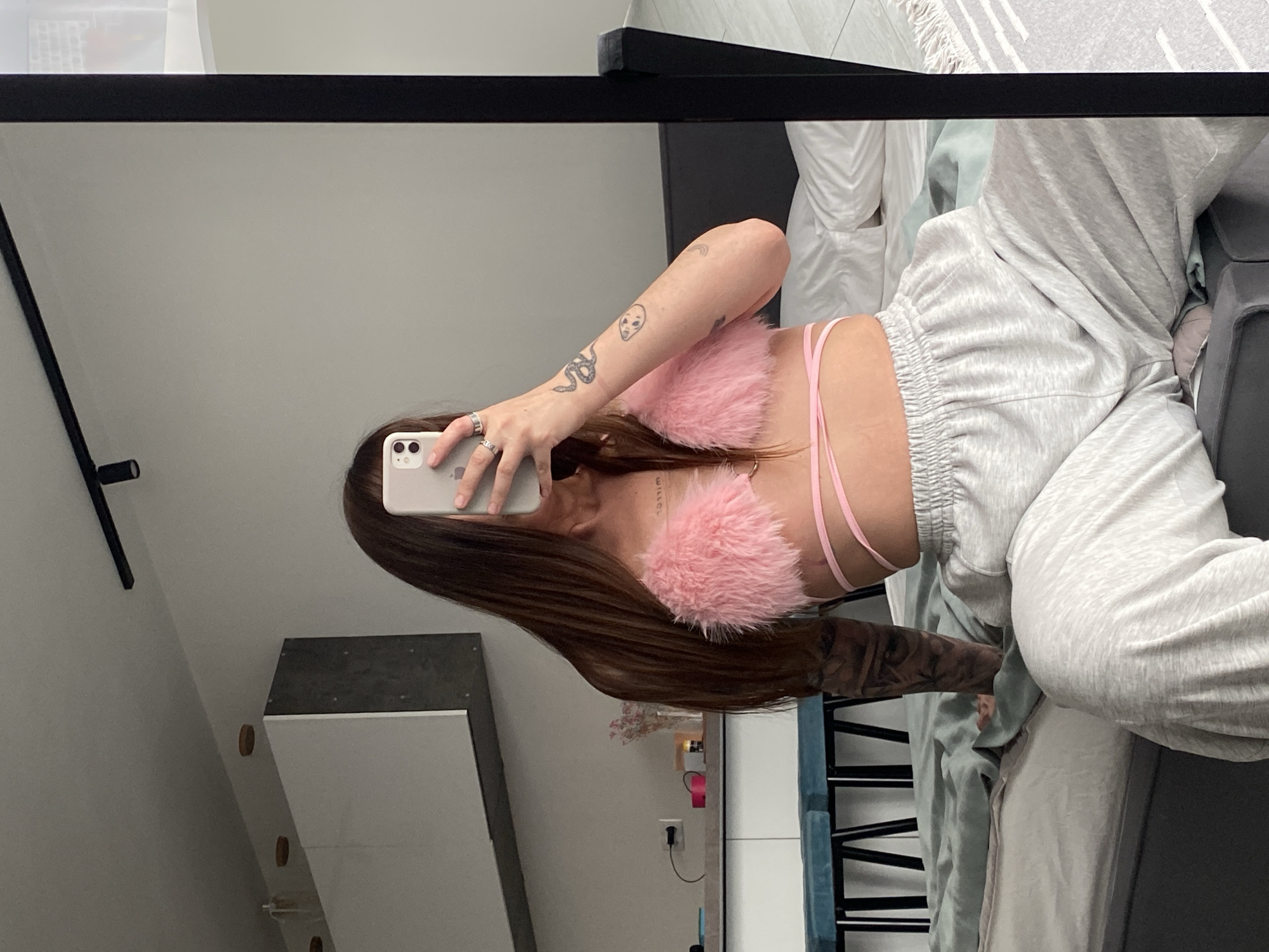 Mirror selfie in a bedroom, pink fuzzy top and grey sweatpants