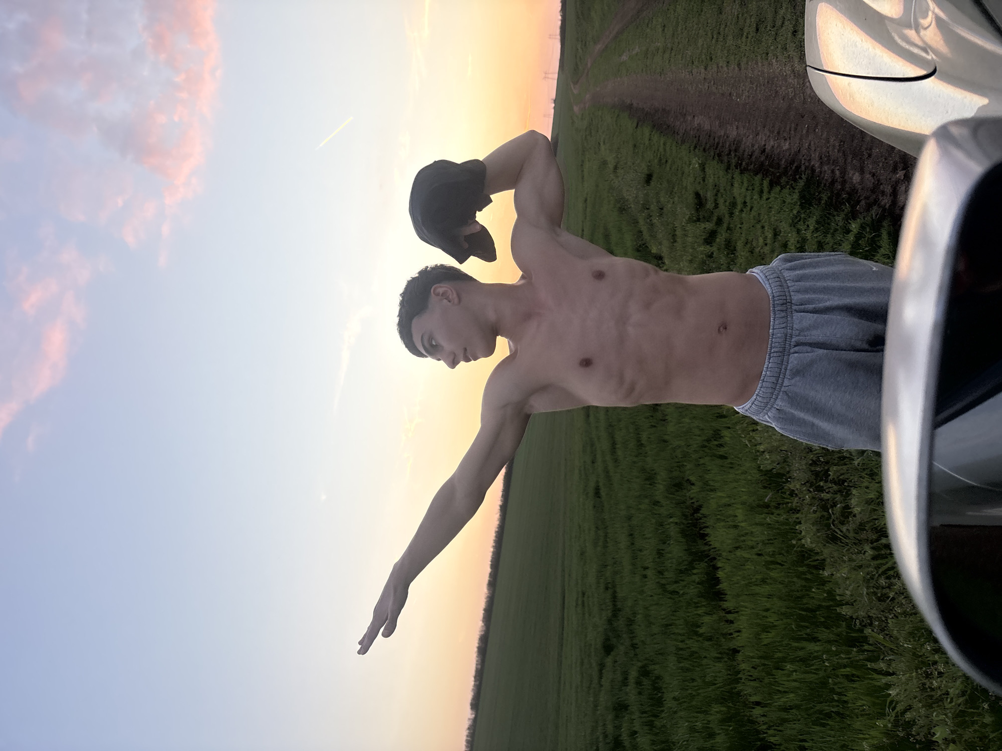 Man poses with car in Bulgarian field at sunset
