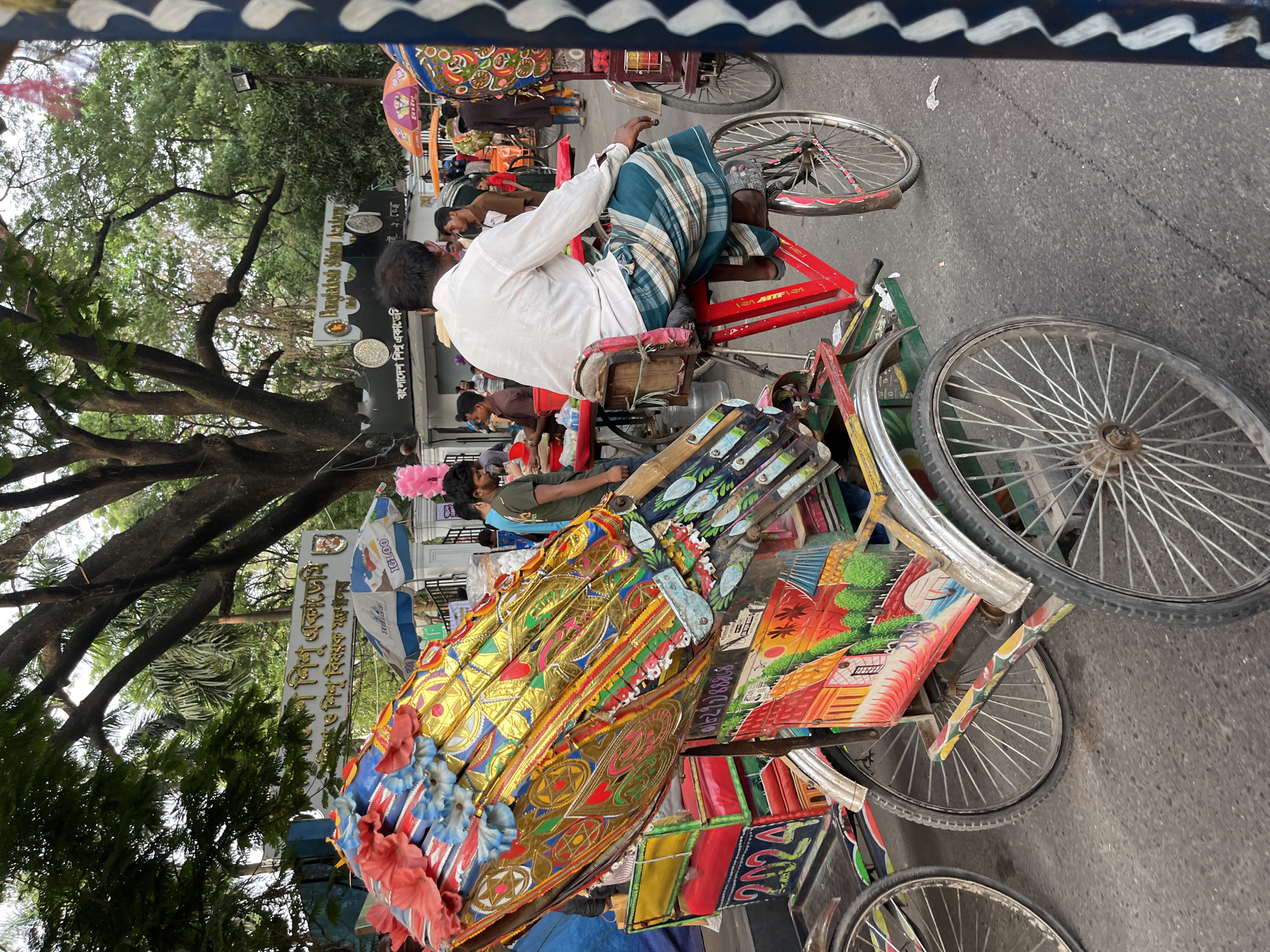 Decorated and loaded rickshaws navigate Dhaka street traffic
