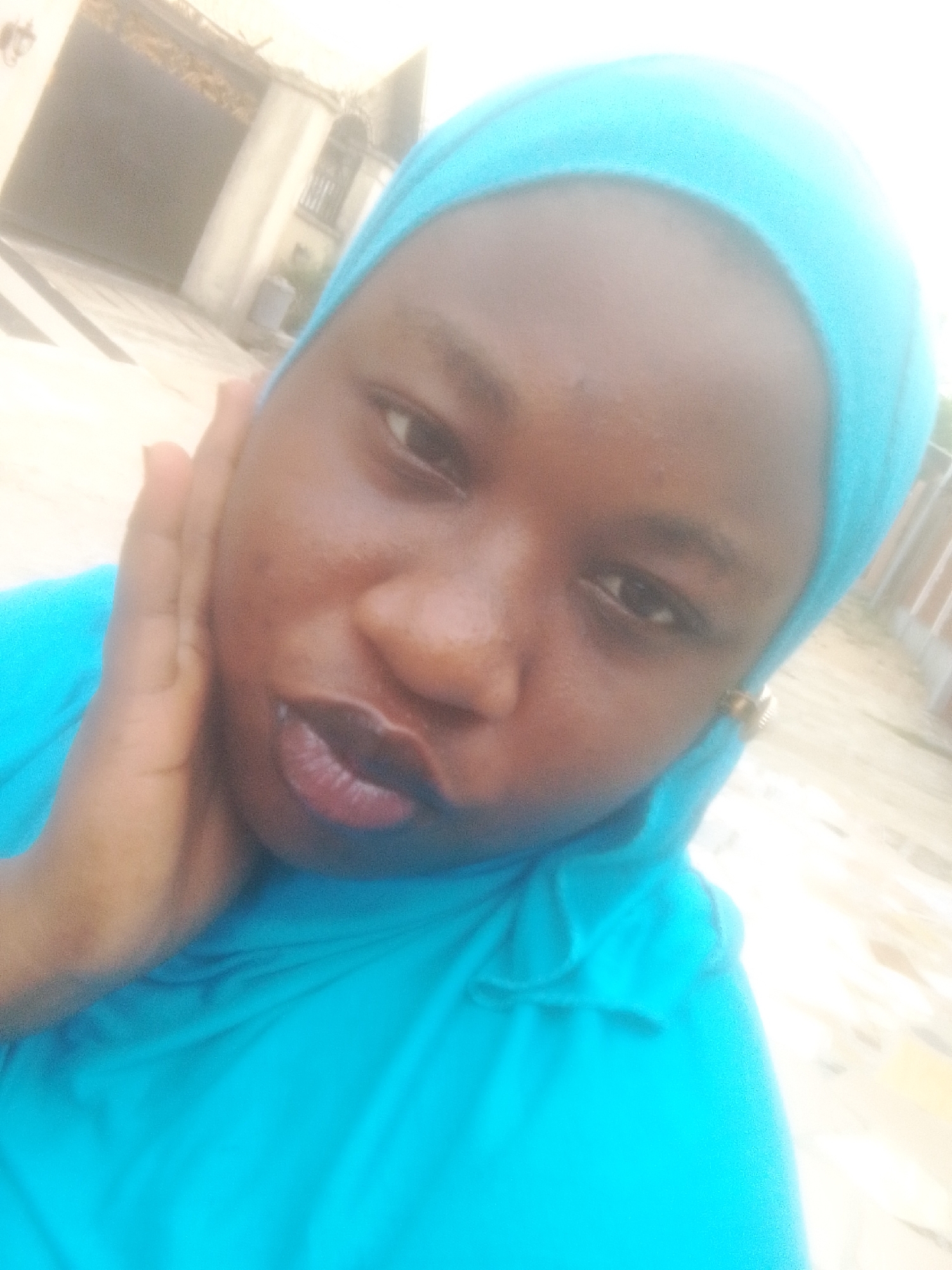 Woman in turquoise headscarf takes outdoor selfie