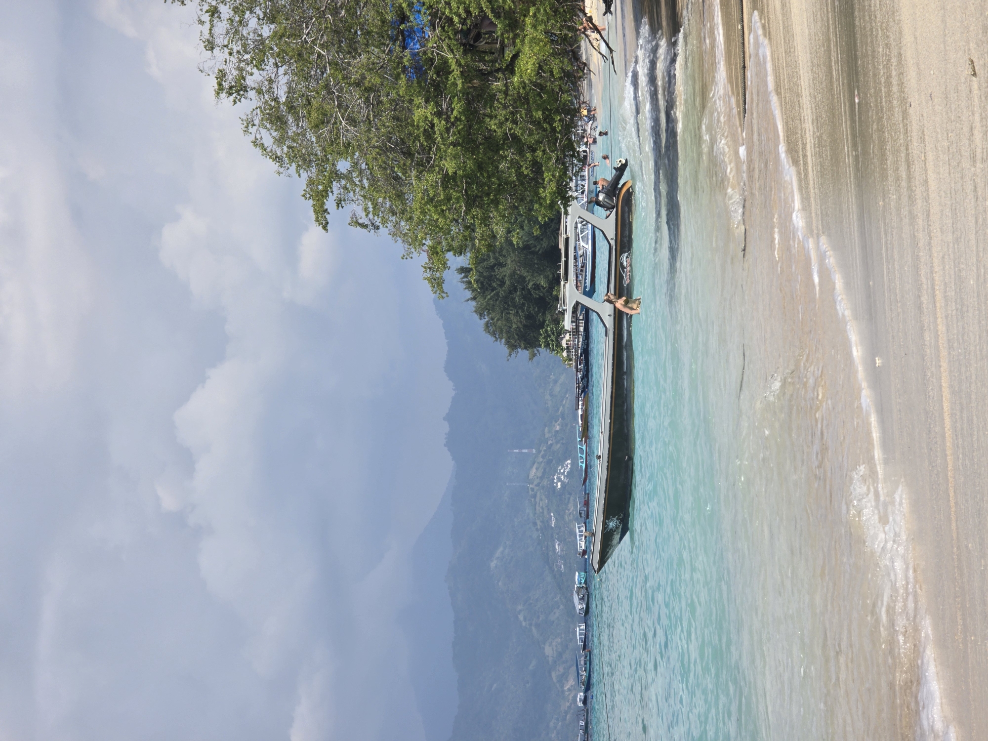 Morning beach scene captured in Indonesia with boats and swimmers