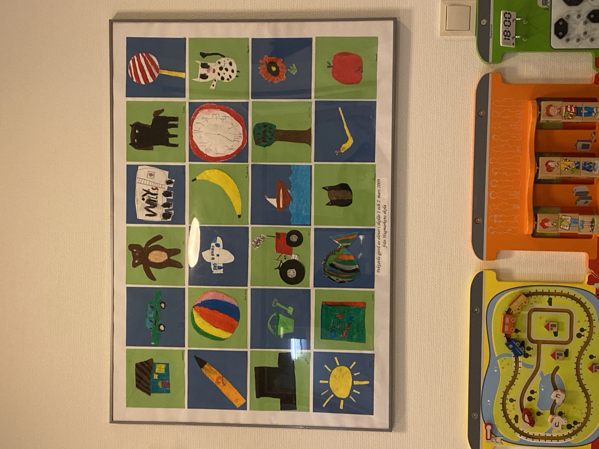 Art display documented in Bälinge featuring children's drawings, watercolors
