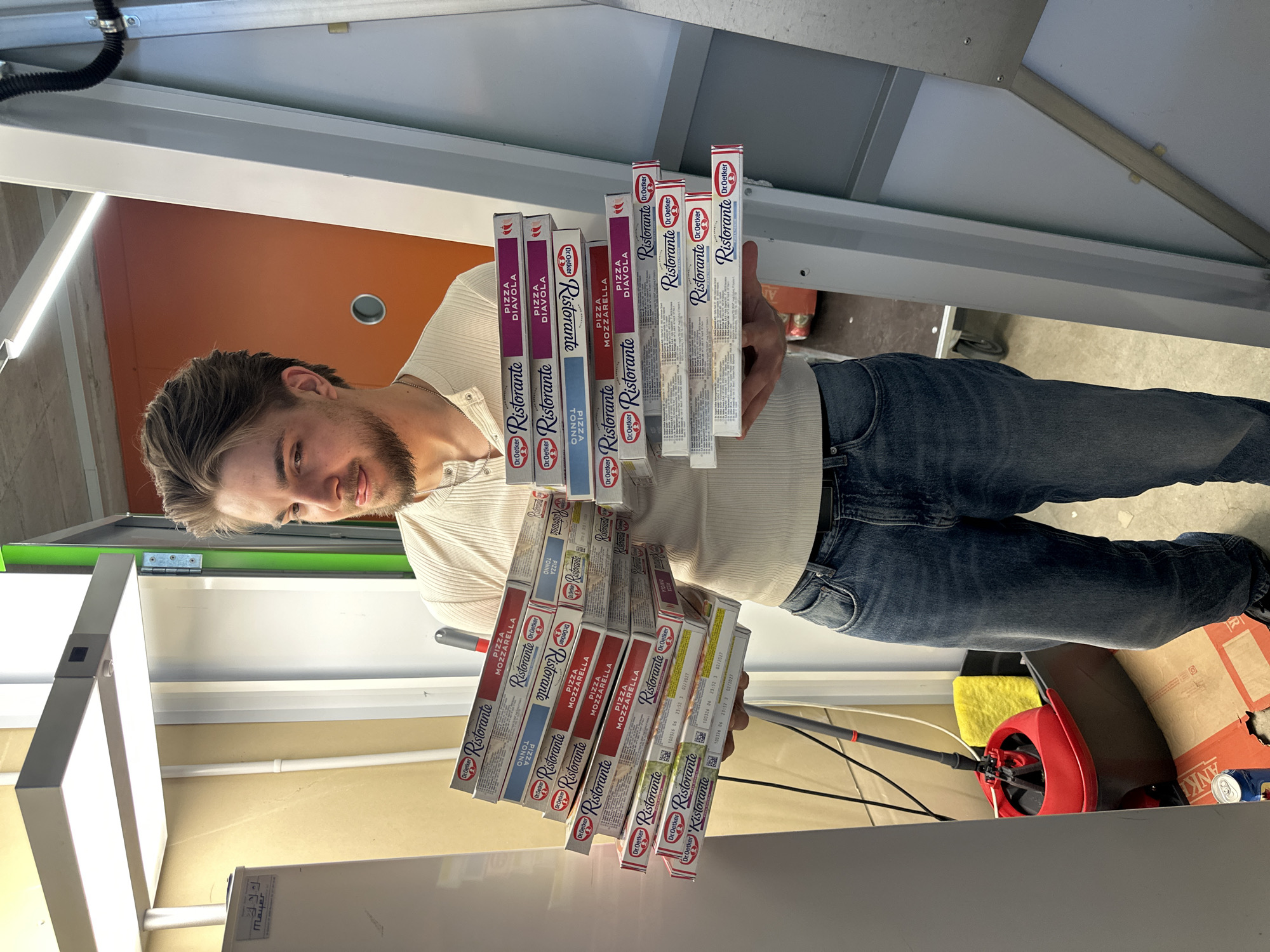 Man holds stack of frozen pizzas in Volketswil