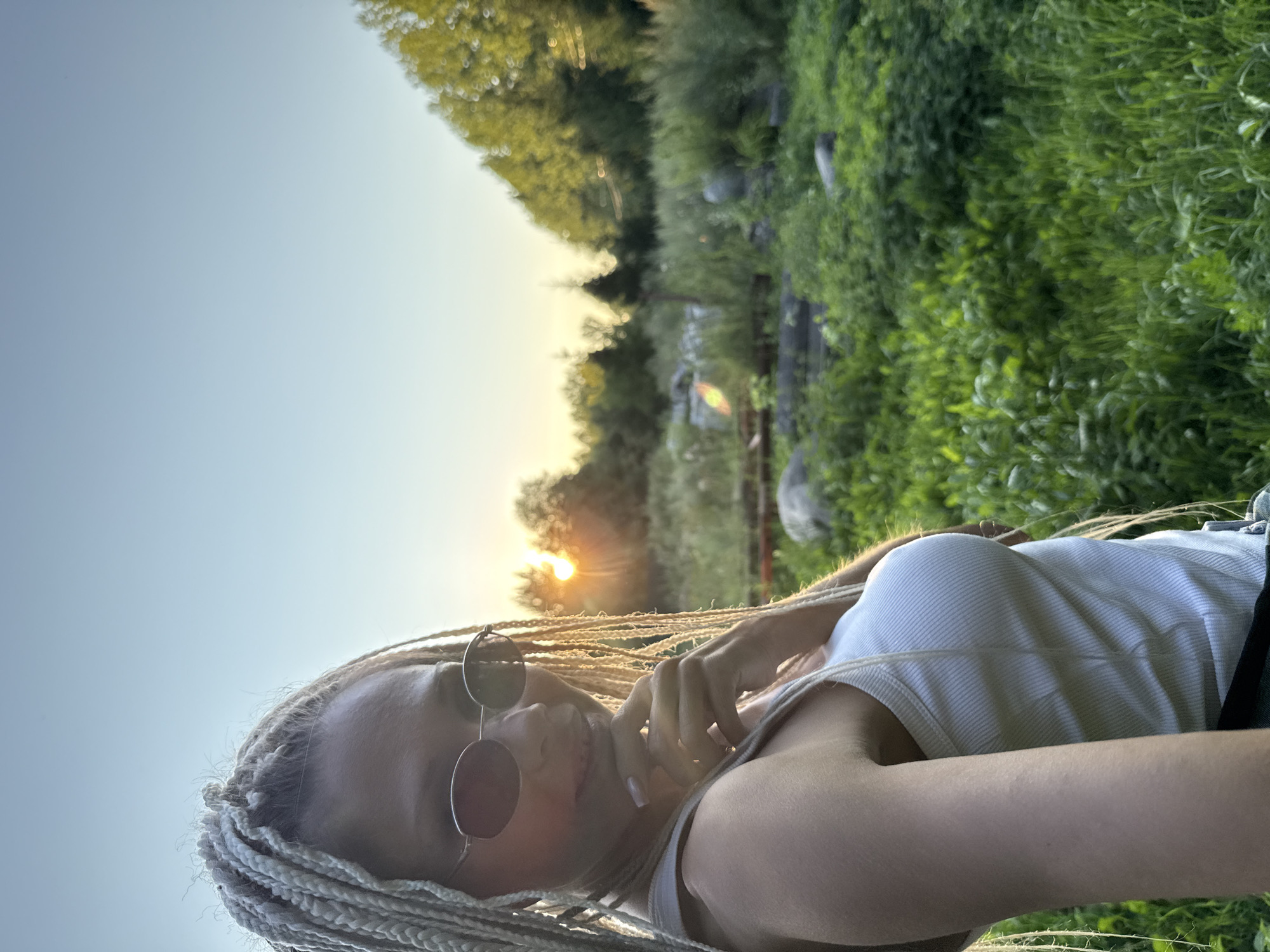 Relaxed pose, braided hair and sunglasses, looking at camera.