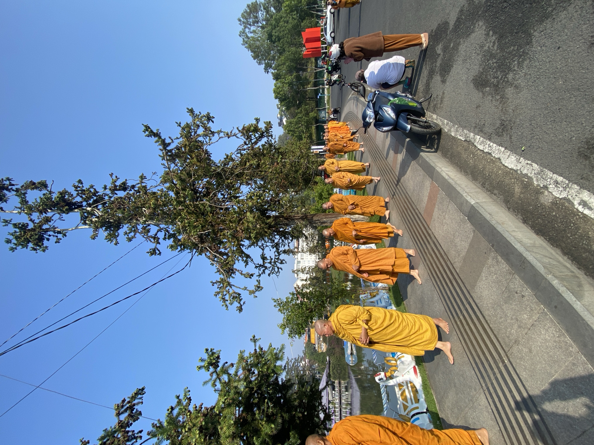 Buddhist monks kneel in street ceremony beside Da Lat lake