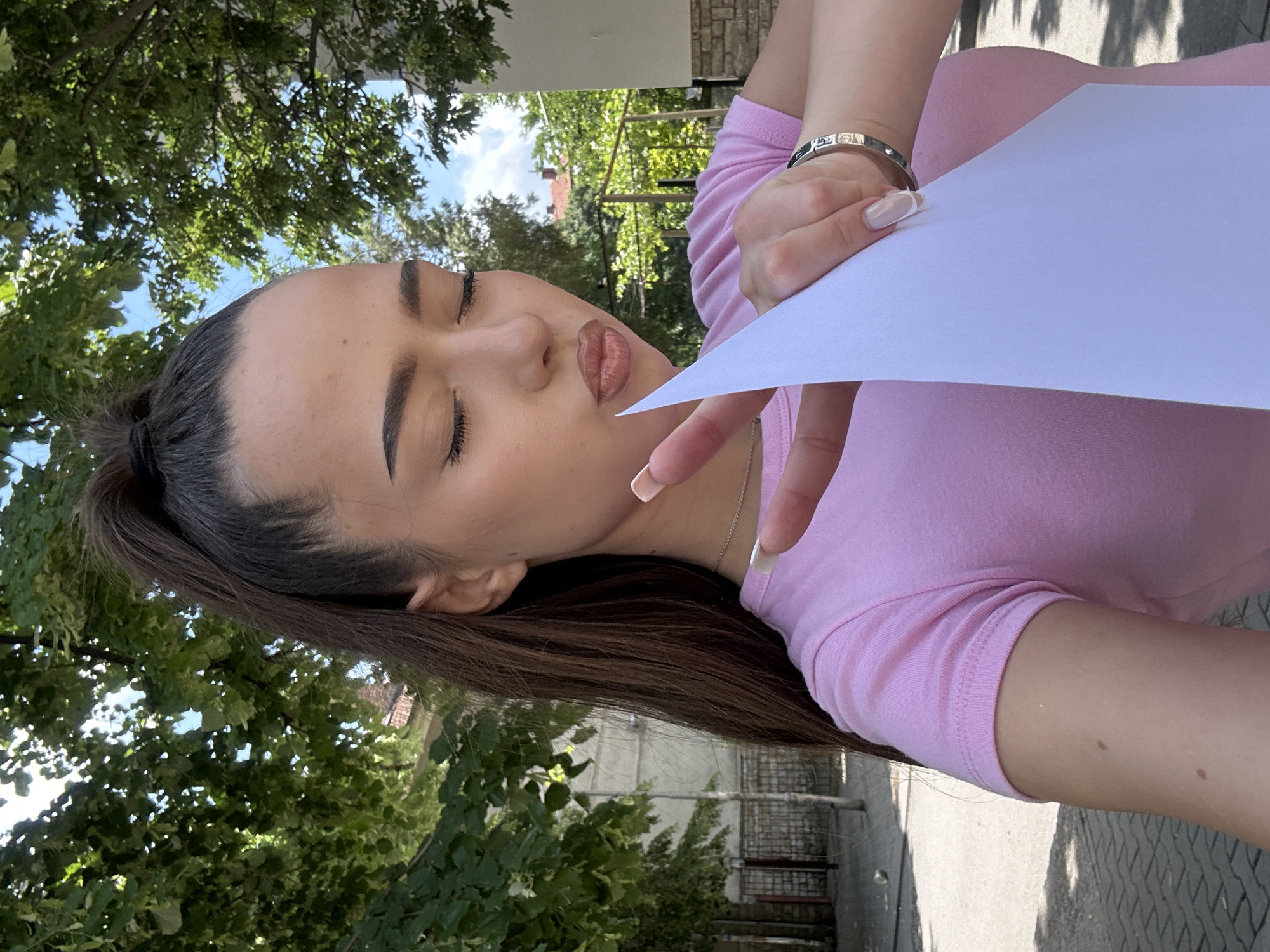 Woman takes outdoor selfies with certificate during brief photo session