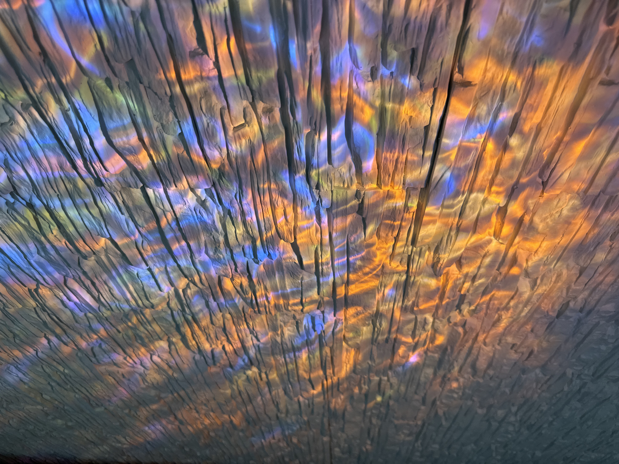 Colorful light show projected onto textured stone wall