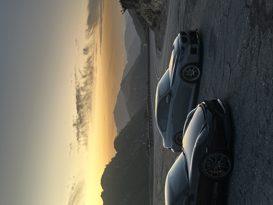 Sports cars gather on Altadena mountain road at sunset