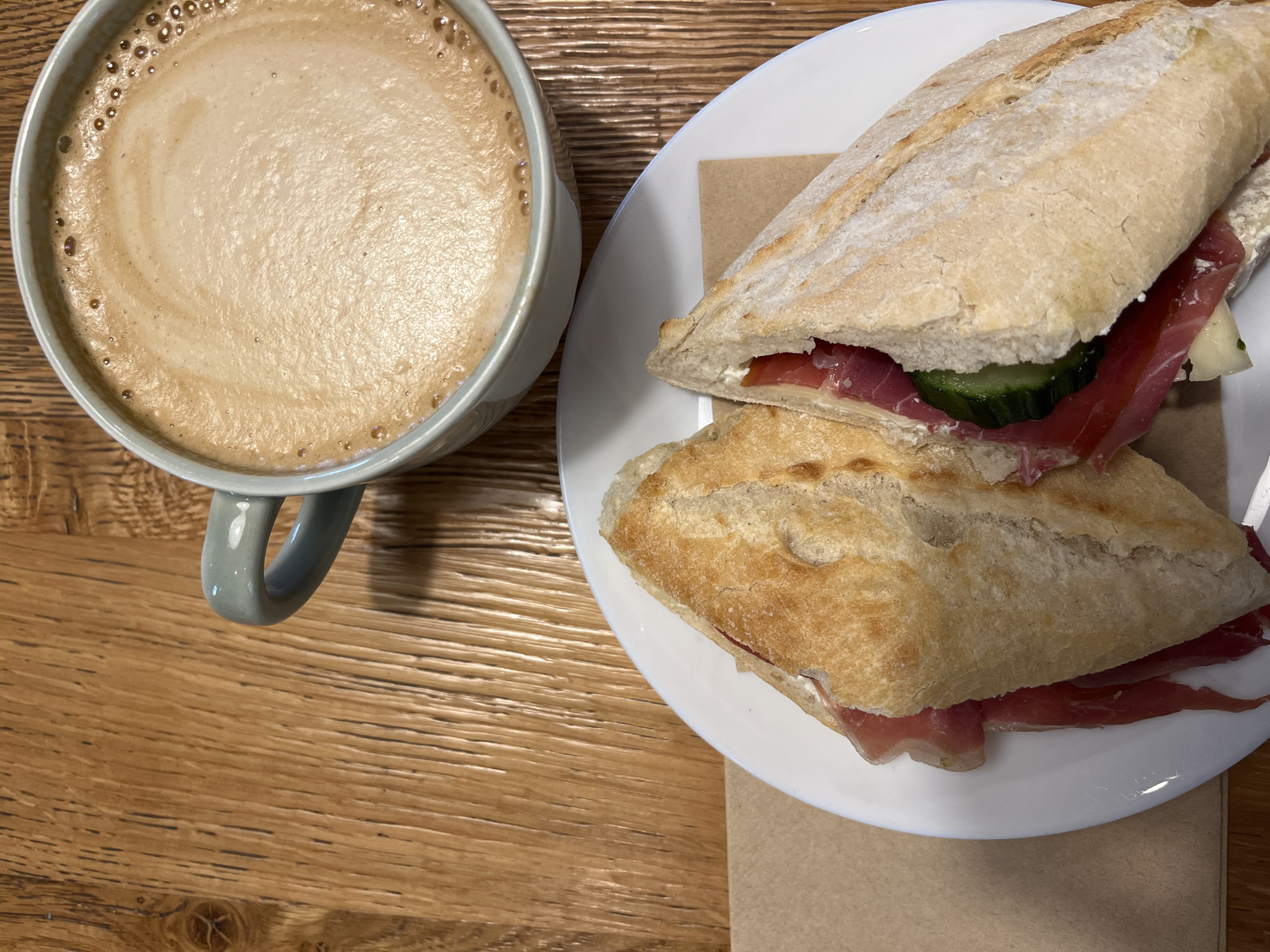 Coffee and sandwich captured on wooden table in Sofia