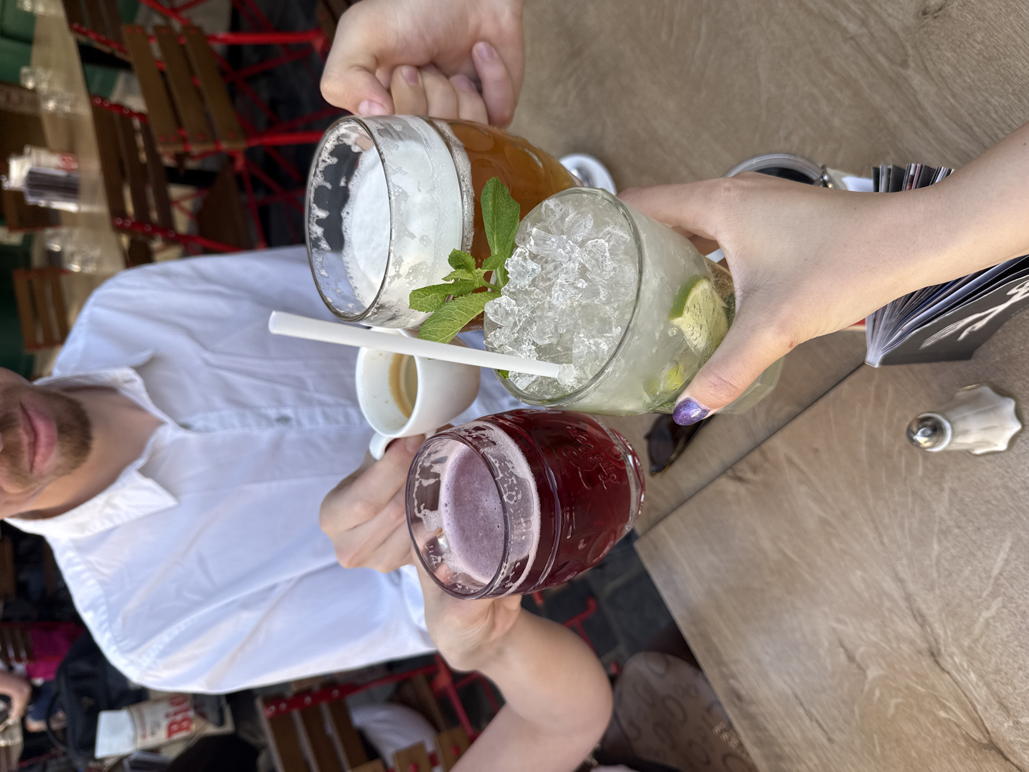 Friends toast with drinks at outdoor table in Budapest