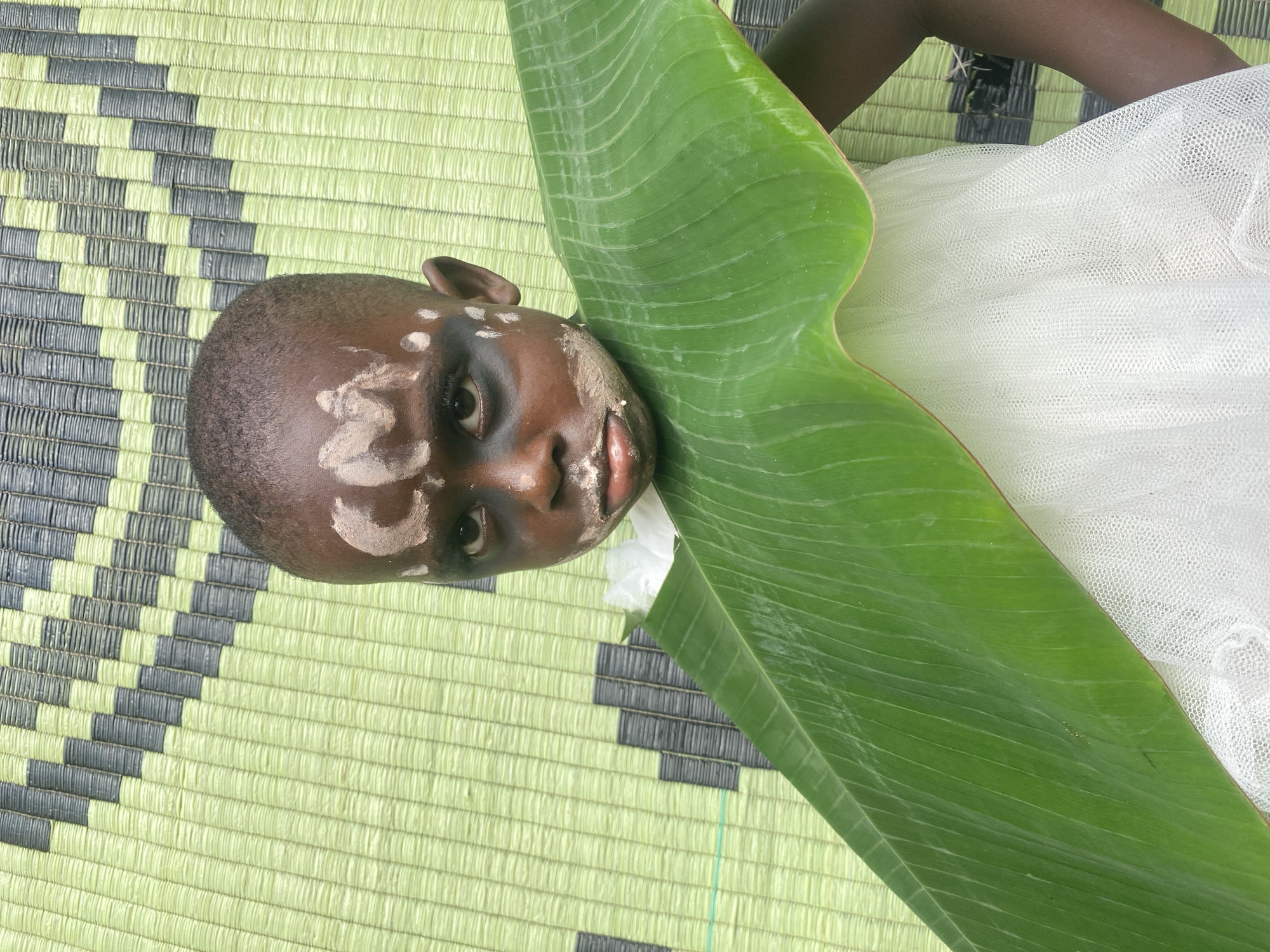 Child with ceremonial face paint rests in Nigerian village