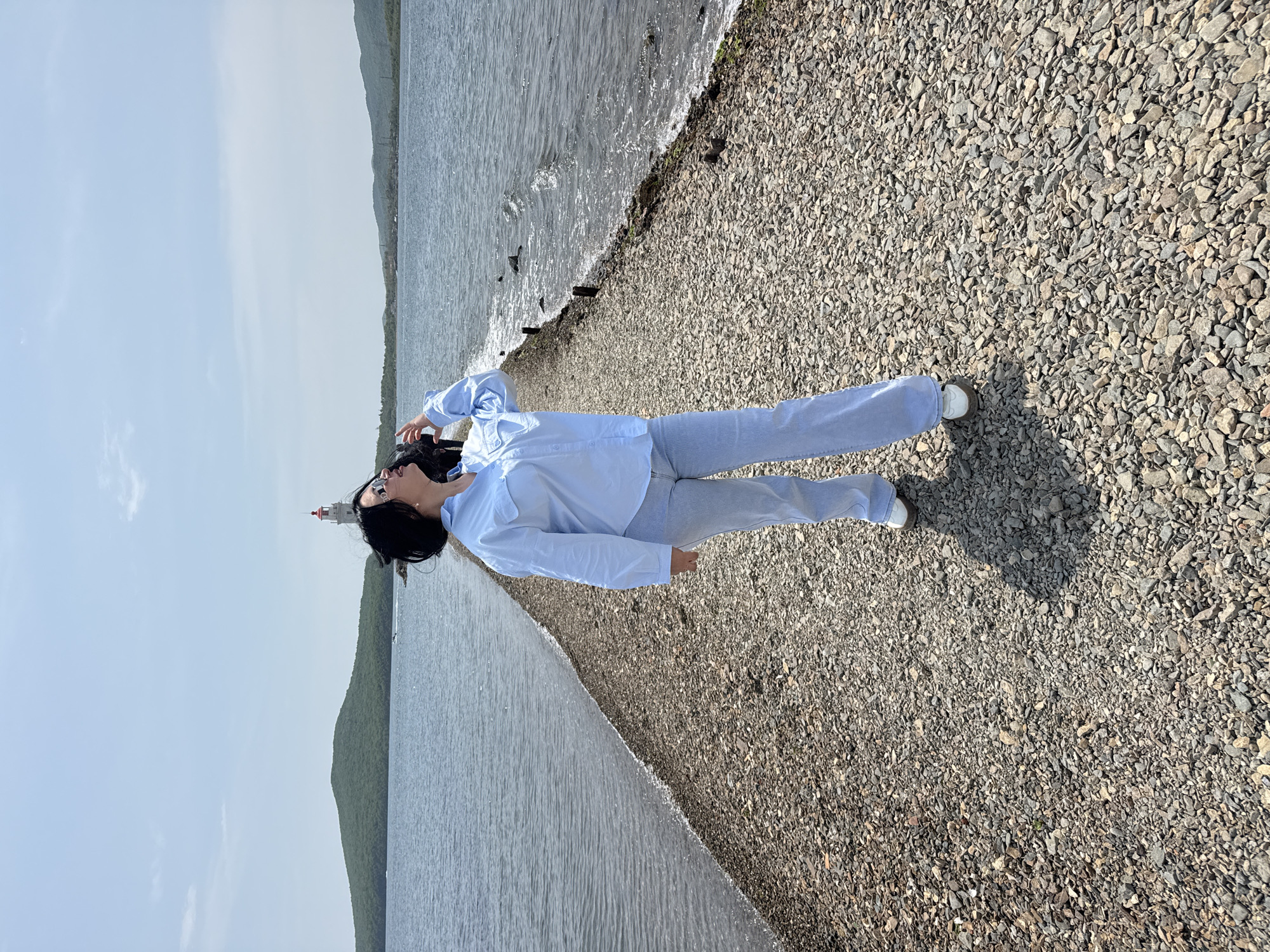Woman relaxes on rocky Vladivostok beach near lighthouse