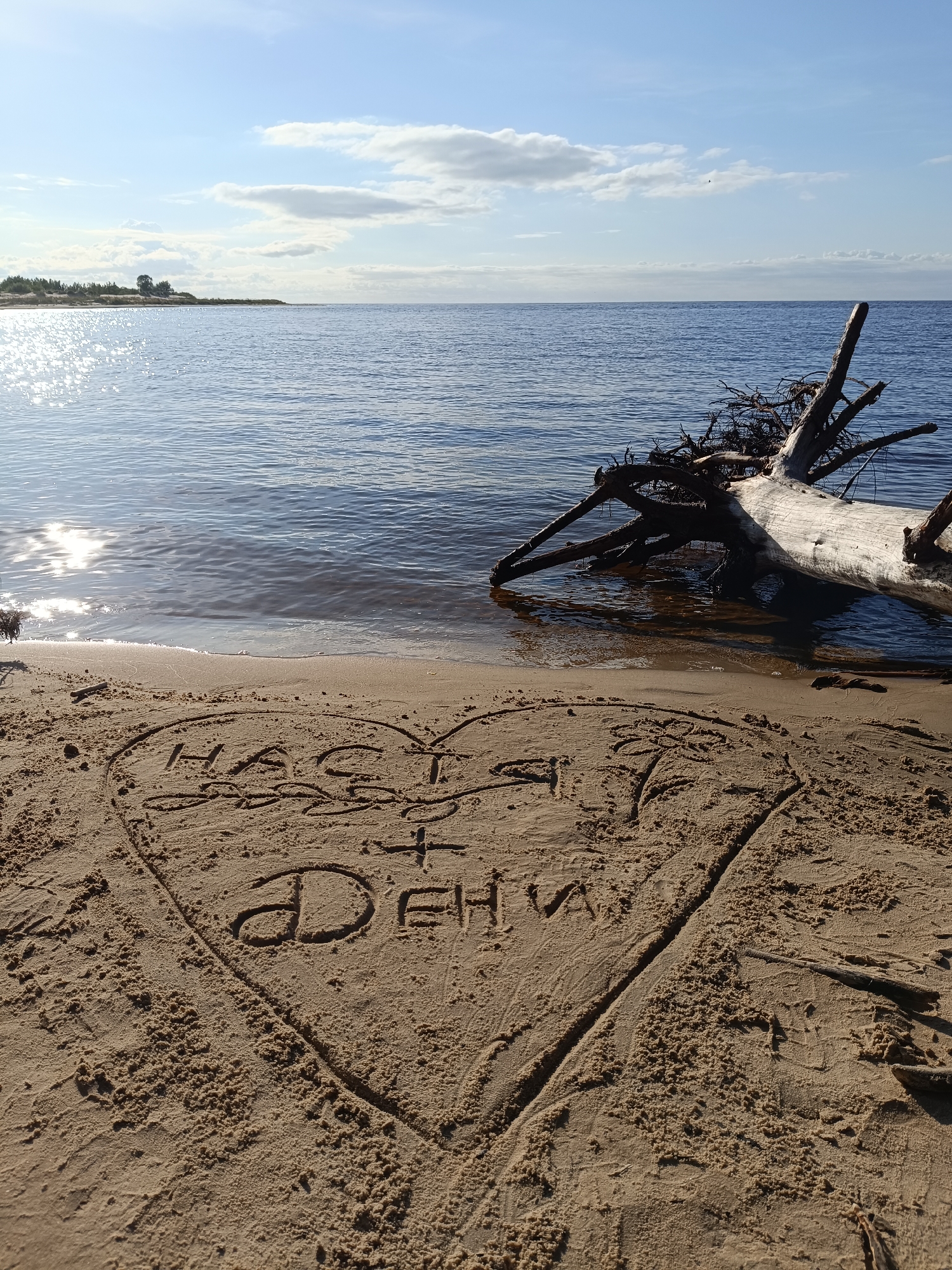 Birthday message written in sand at a waterside beach.