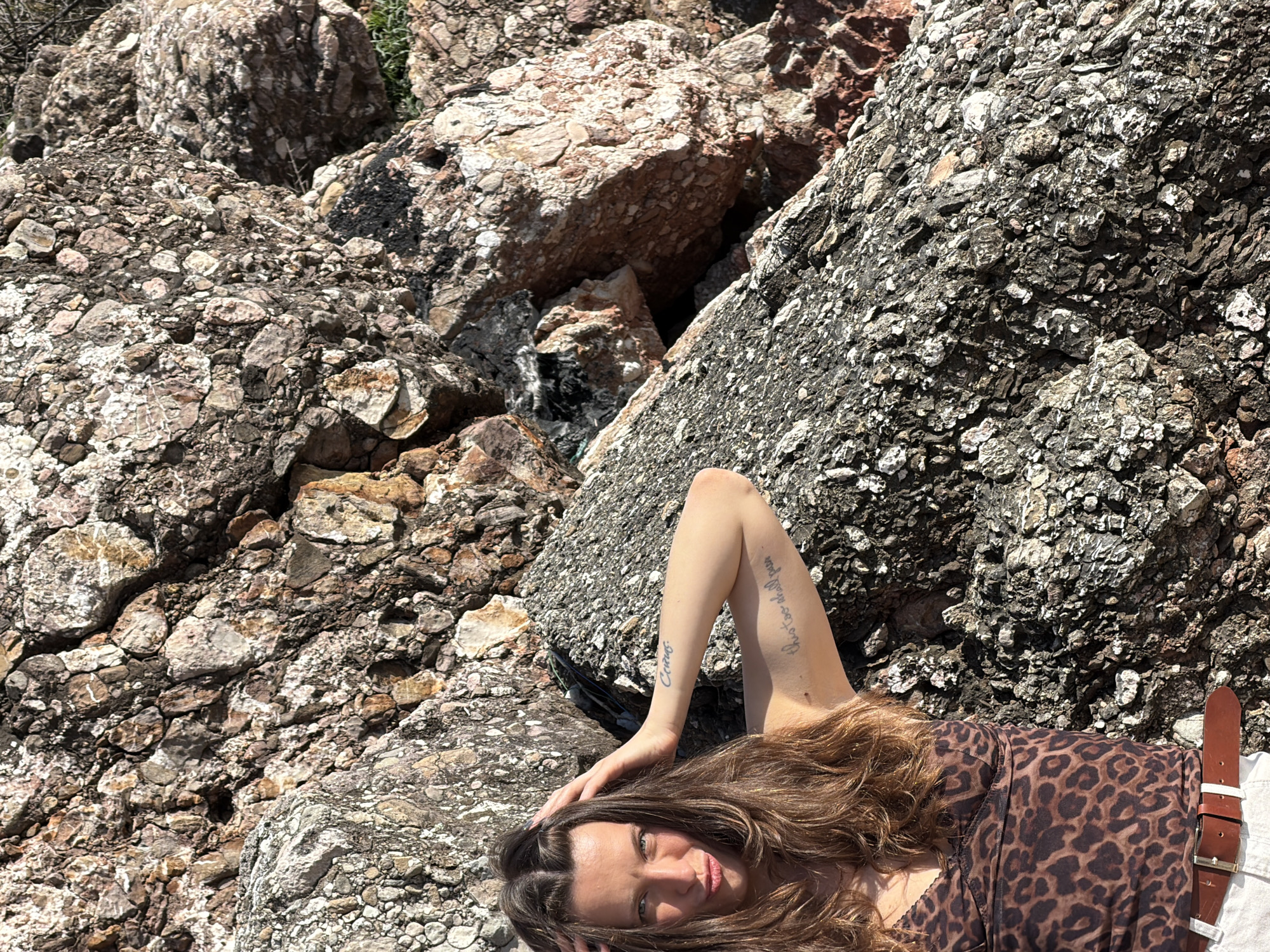 Woman rests on rocks in Sveti Stefan, Montenegro