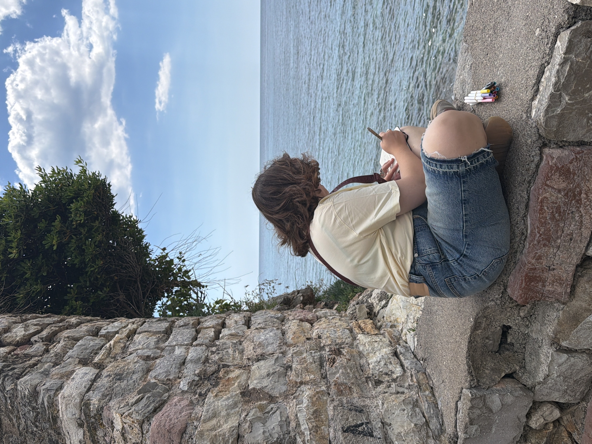 Artist sketches seaside scene on stone wall in Budva