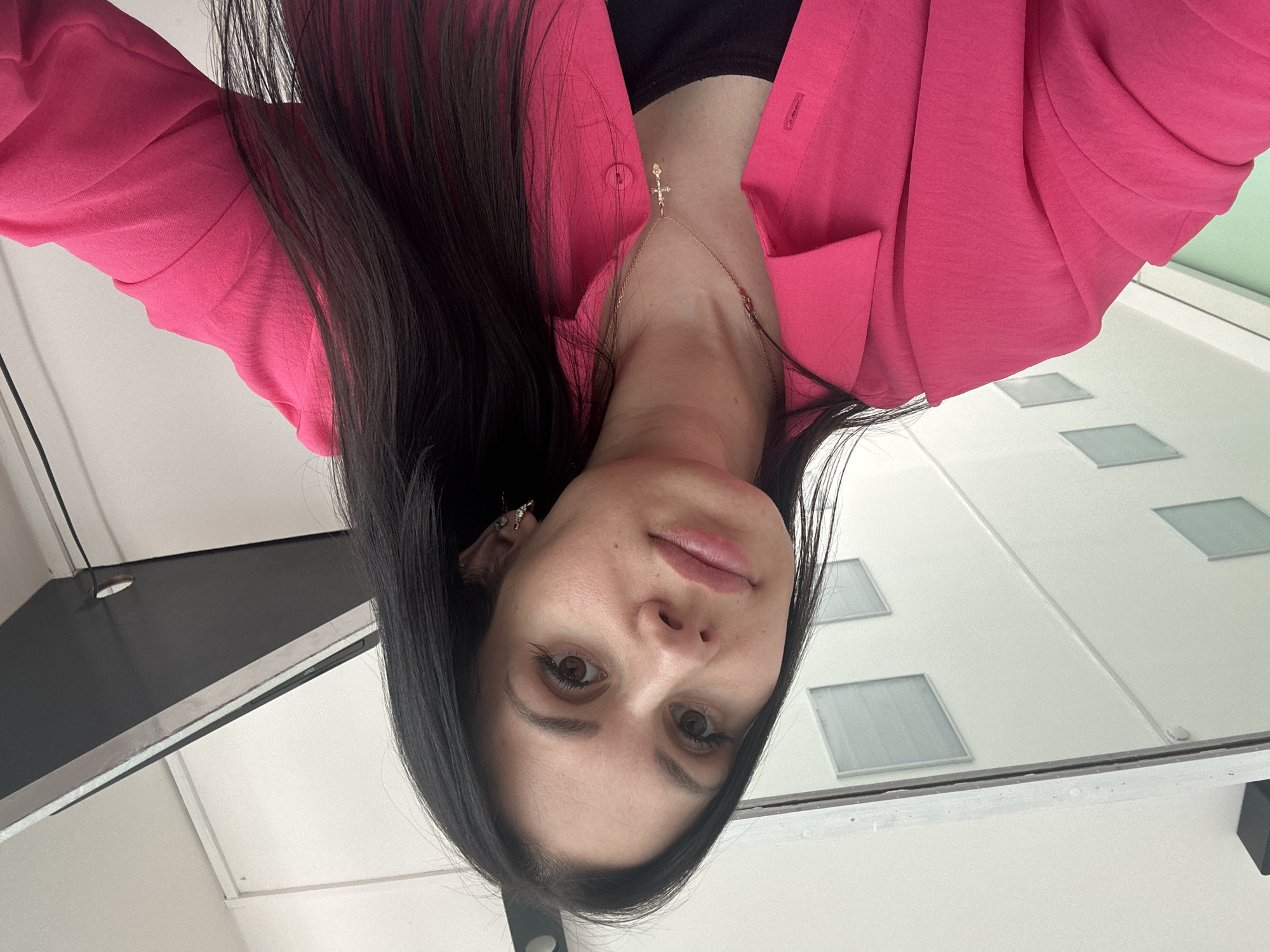 Woman photographed in upside-down selfie wearing pink blazer