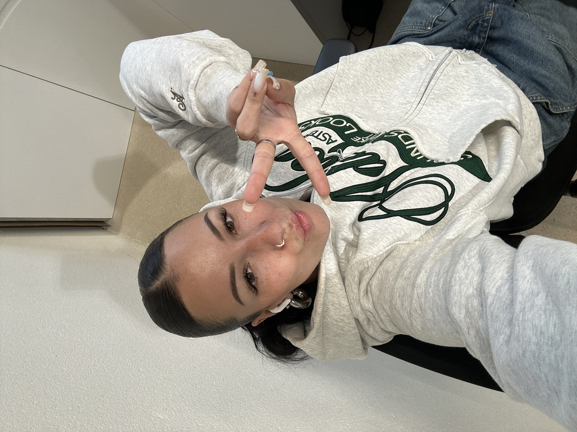 Woman poses for selfies in Paris wearing gray hoodie