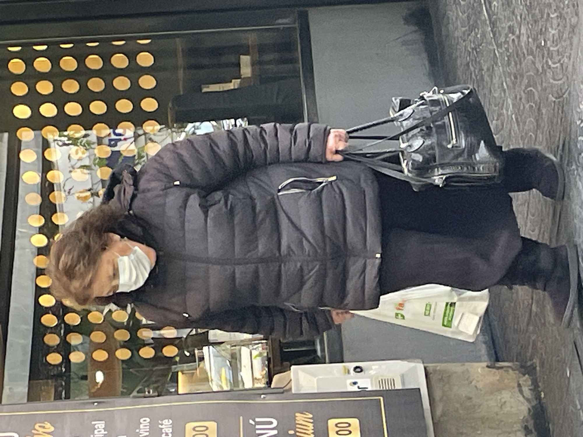 Elderly woman walks Buenos Aires sidewalk carrying bag