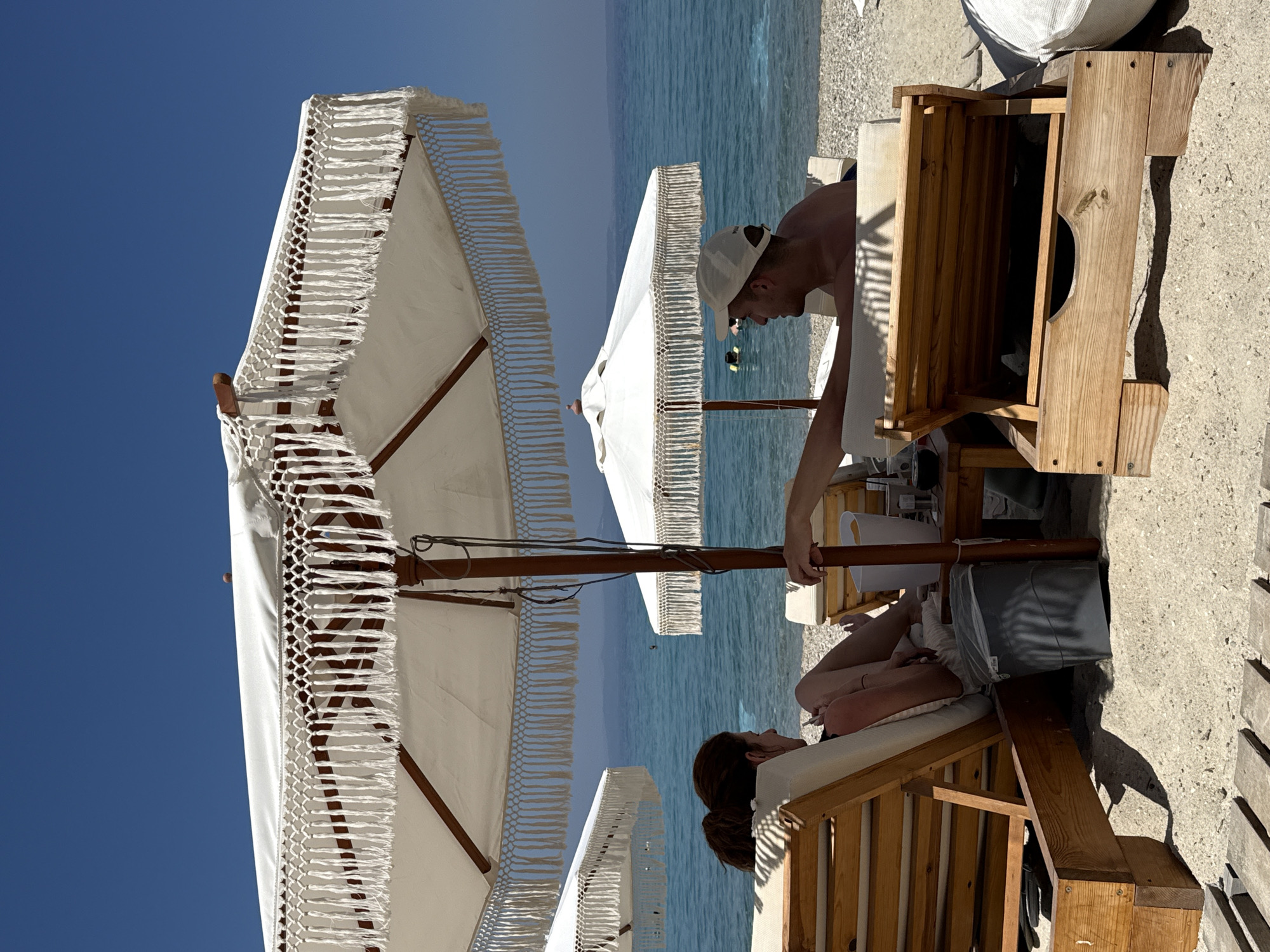 Lazy afternoon on a Greek beach under white fringed umbrellas